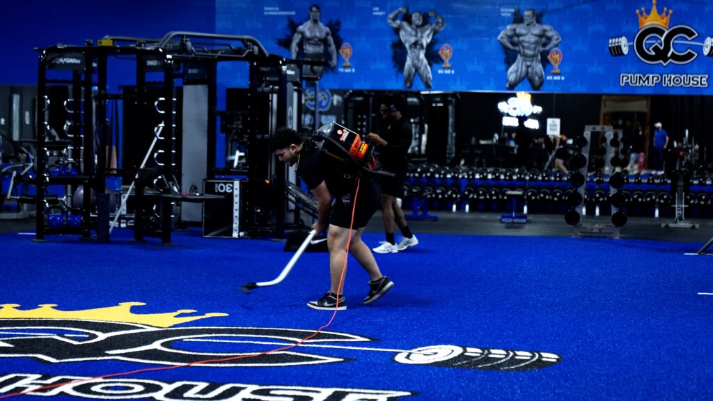 Gym staff vacuuming turf in gym